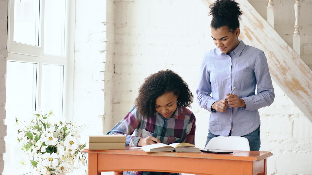 Tutor guiding a student through her work at a desk