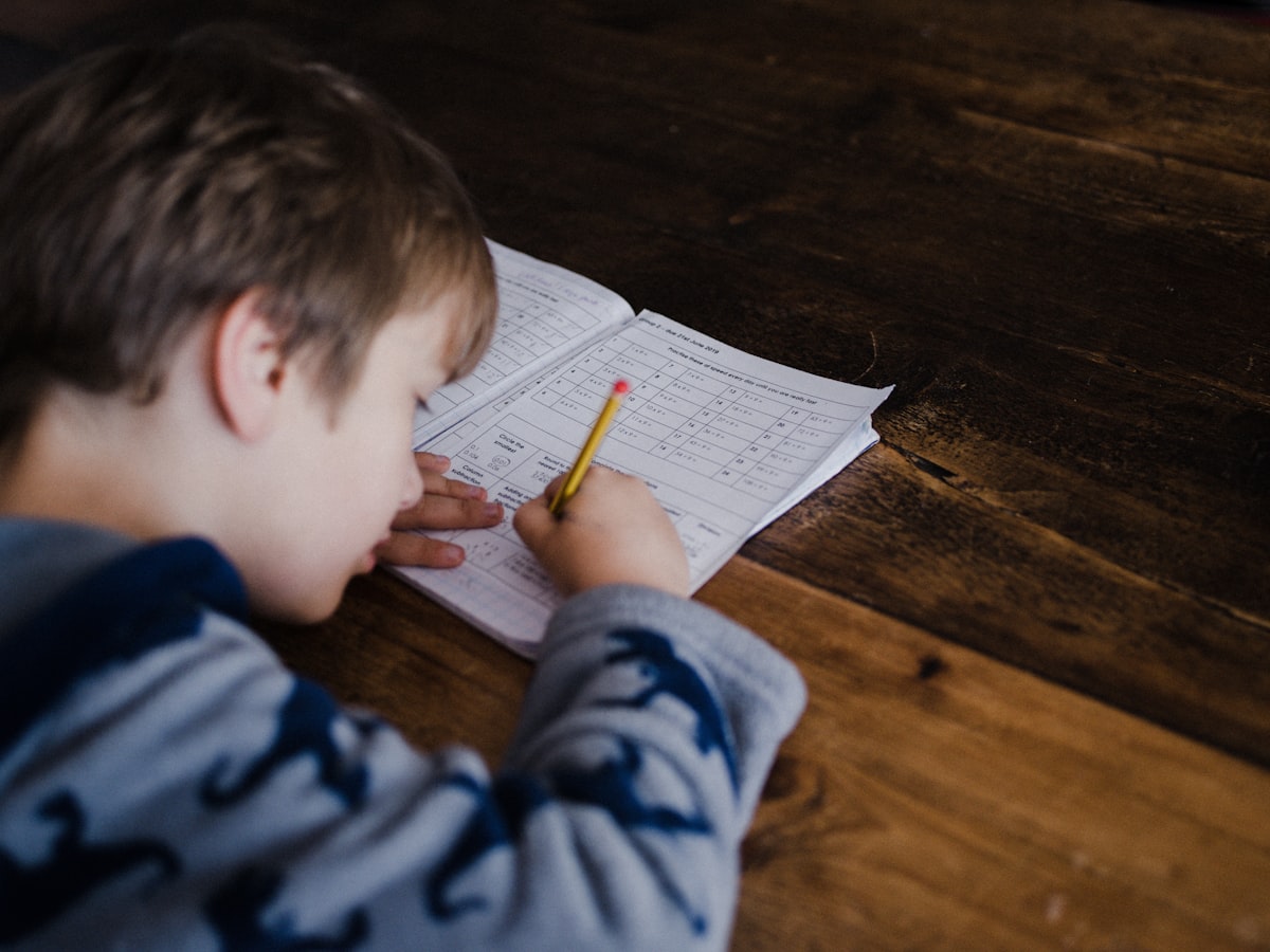 Young student writing in a math workbook